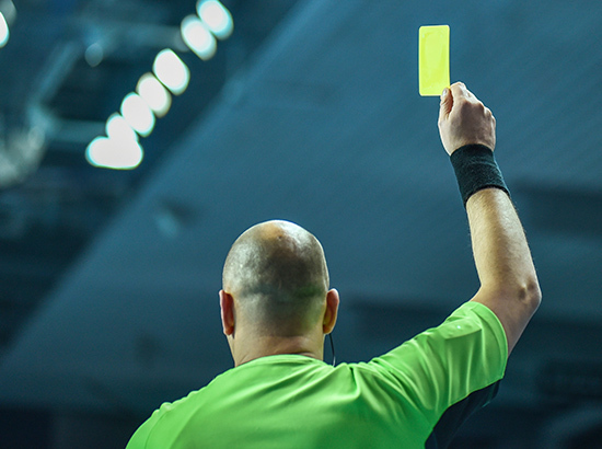 Arbitre qui tend un carton jaune